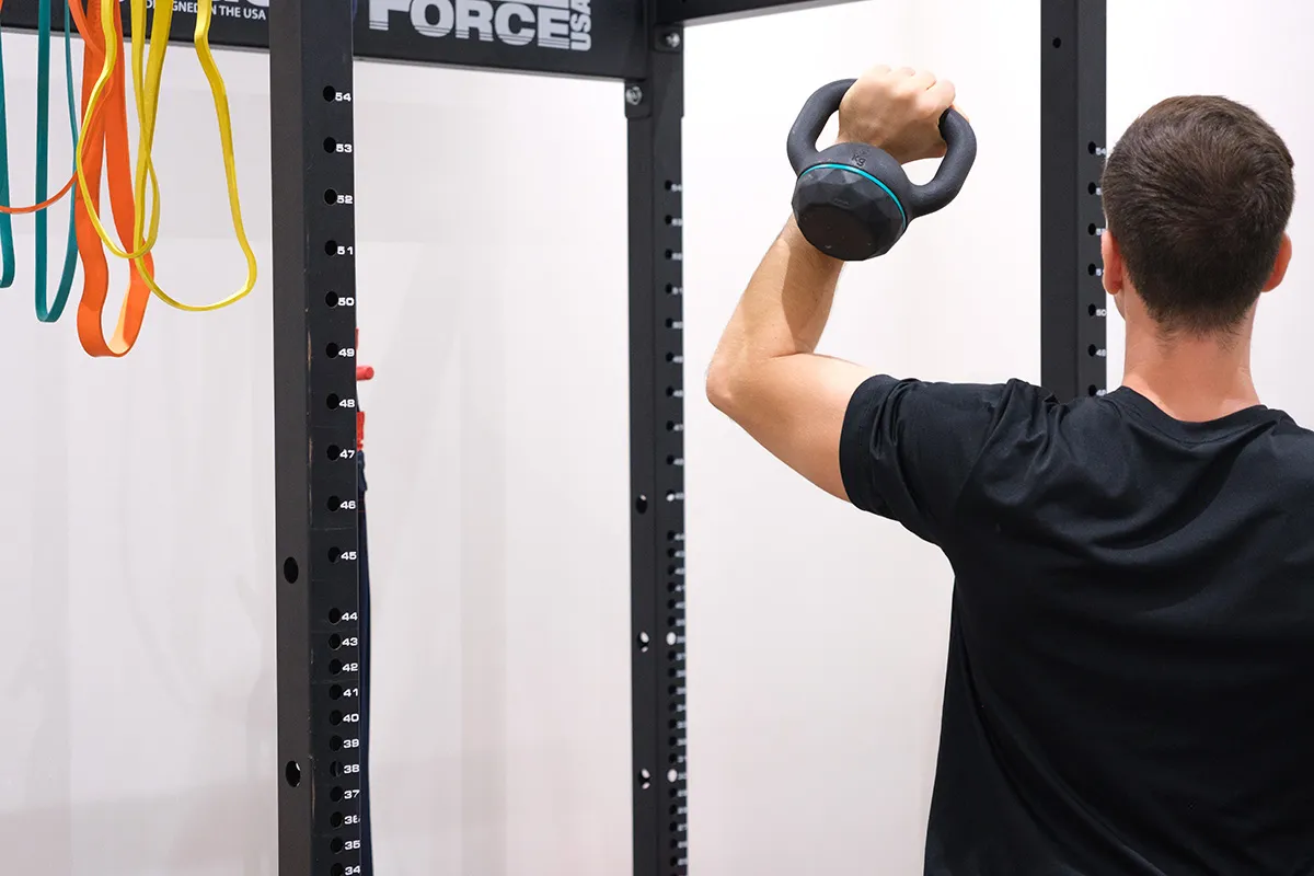 Paciente realizando ejercicio terapéutico con kettlebell en la zona de readaptación